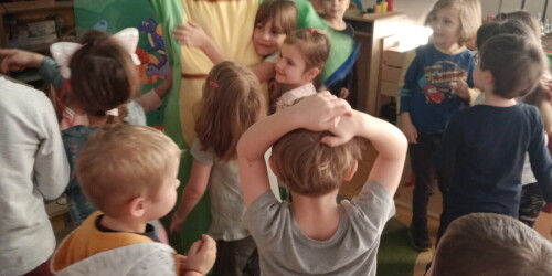 Dzieci bawią się z pluszowym dinozaurem.pl
